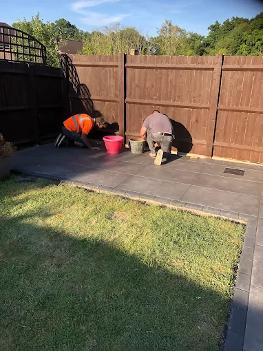 Two builders laying a porcelain patio in a Sussex garden