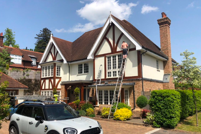 M. Ross roofer on a ladder working on a Tudor-style Brighton home